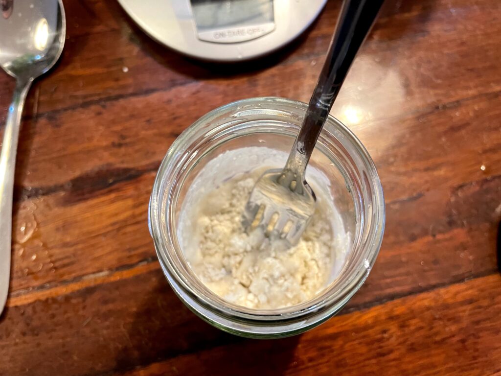 A dry, lumpy mixture in a glass jar with a fork in it